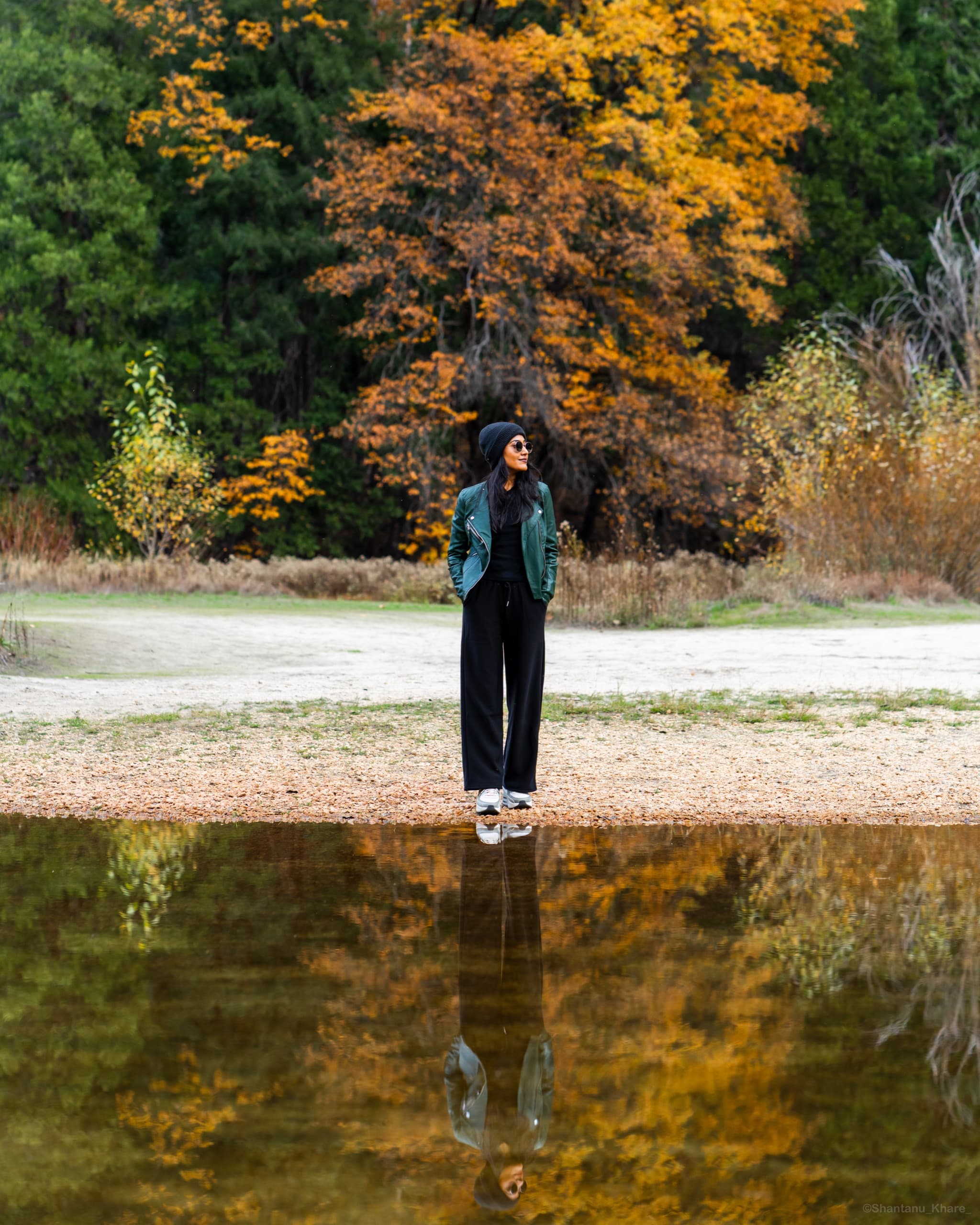 Portrait photography — a woman mirrored in a still lake among autumn trees.