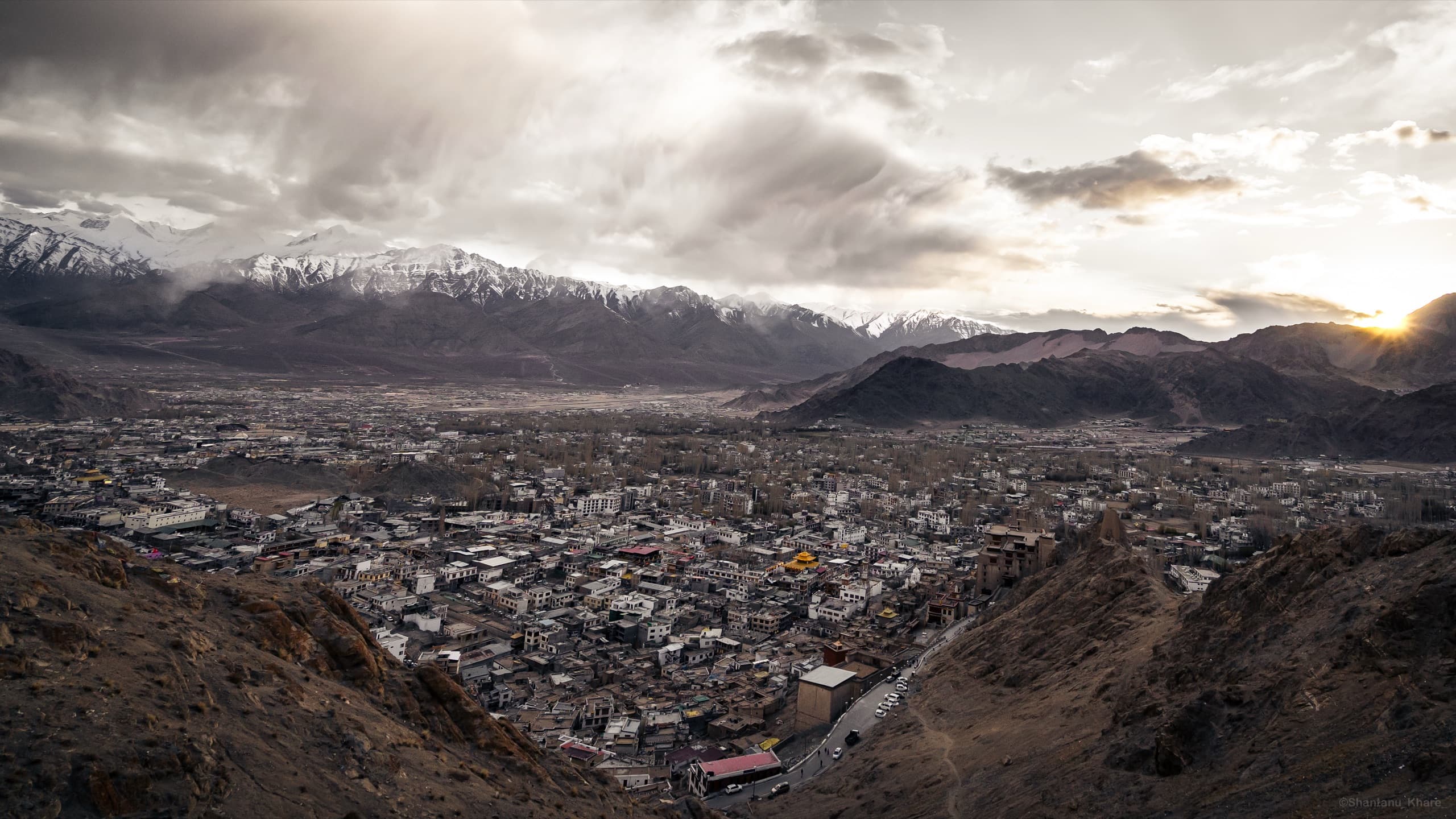 Travel photography — sunset over the Leh valley beneath snow-lined Himalayan ridges, Ladakh.